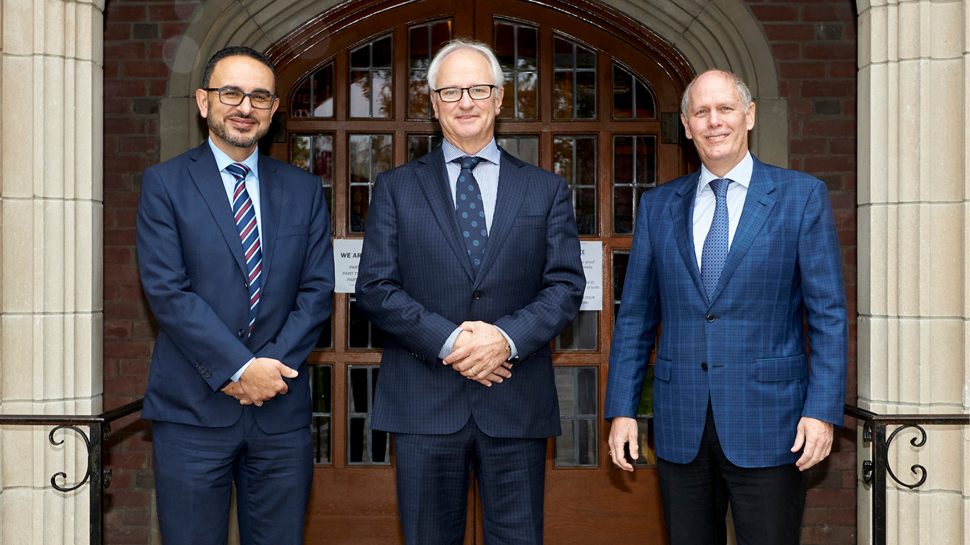 Three smiling professionals standing together.