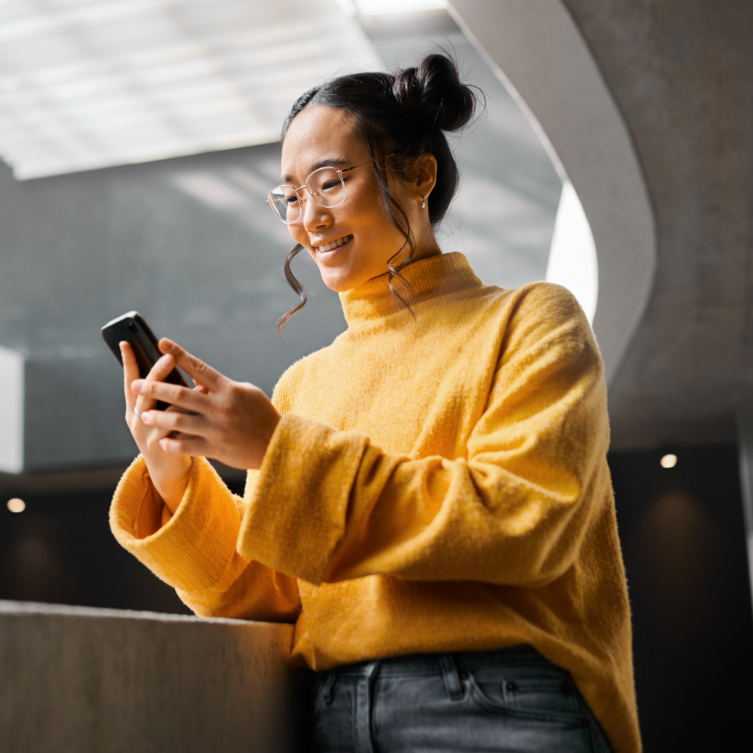 A smiling student using a cell phone.
