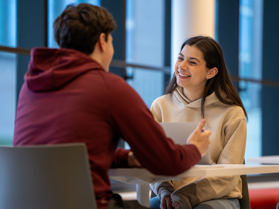 A student smiling as they speak to an advisor.