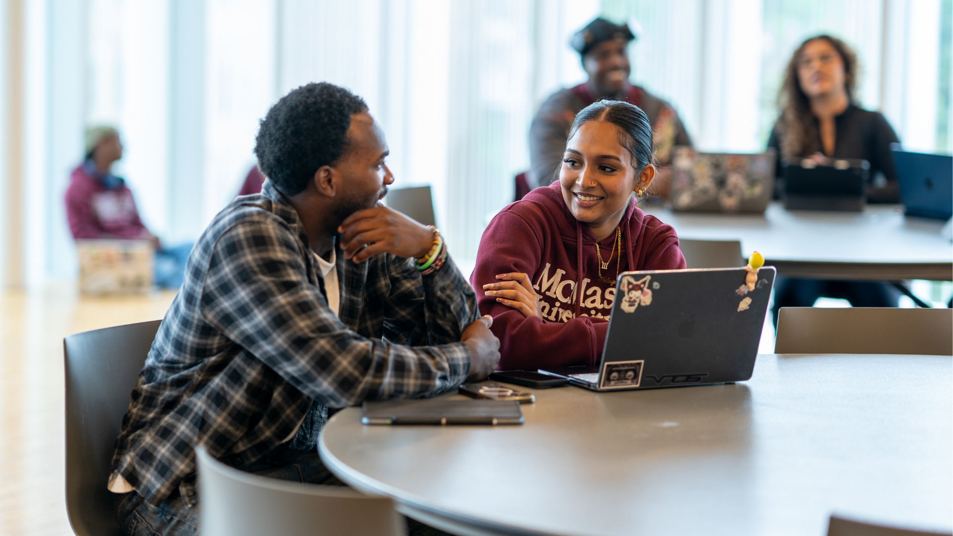 Two students having a conversation over a laptop.