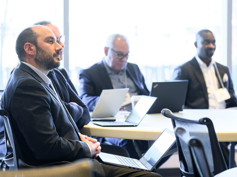 A group of executives listening to a speaker in a boardroom.