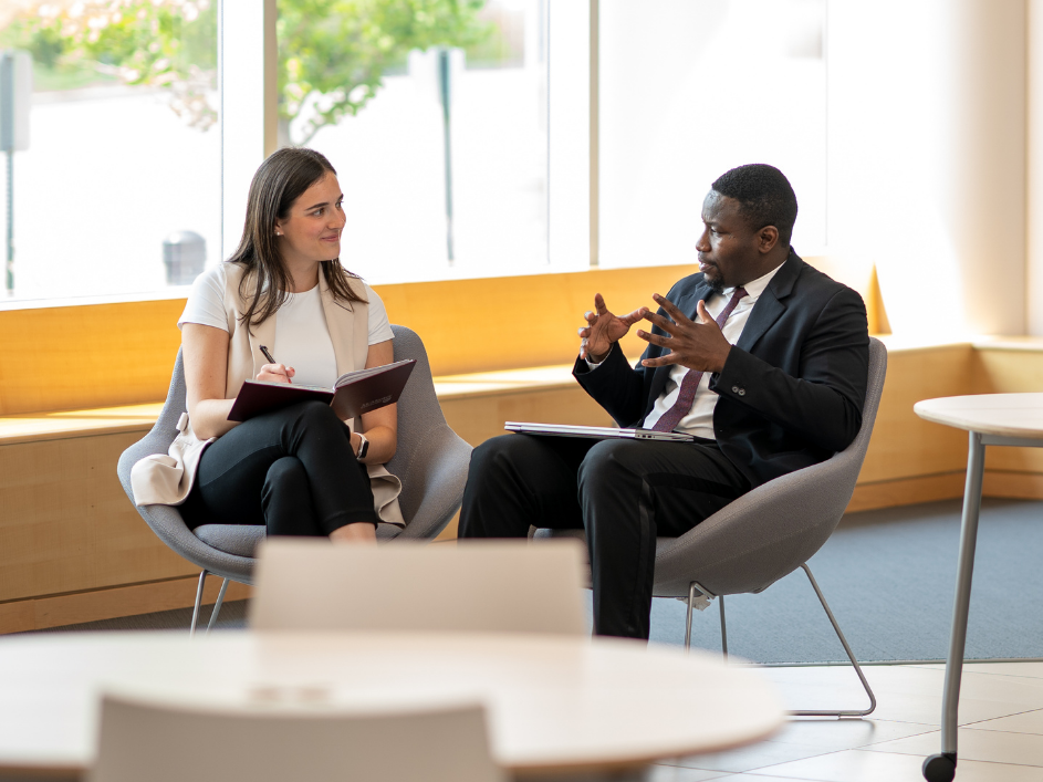 A businessman speaking to a staff member taking notes.